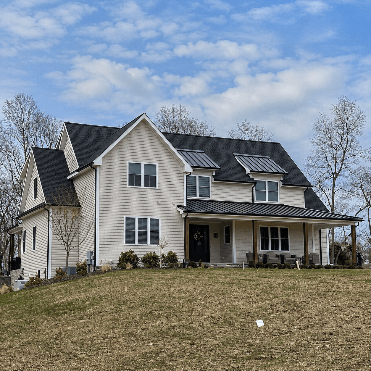 Light-toned siding across a gabled two-story home with a black standing-seam metal porch roof and a wraparound covered porch.