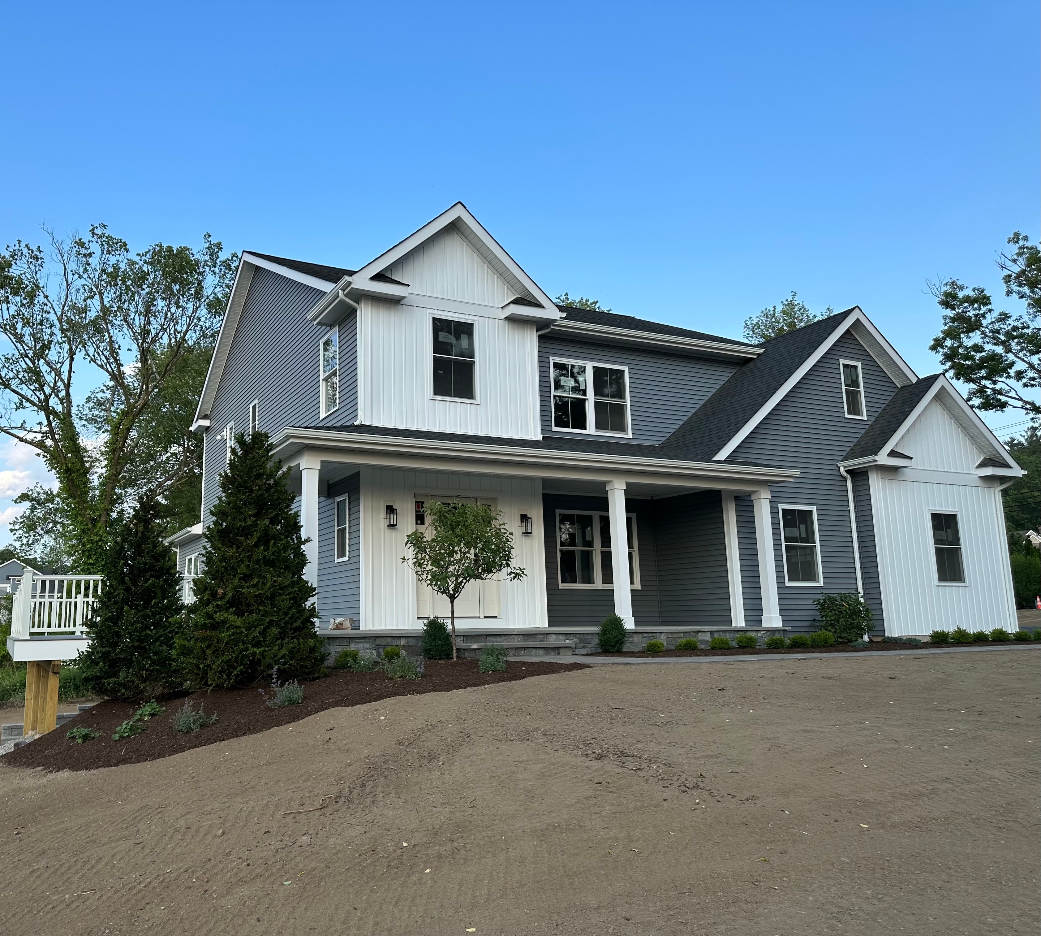 Blue-gray home combining vertical board-and-batten gables with horizontal siding, white trim and a covered front porch.