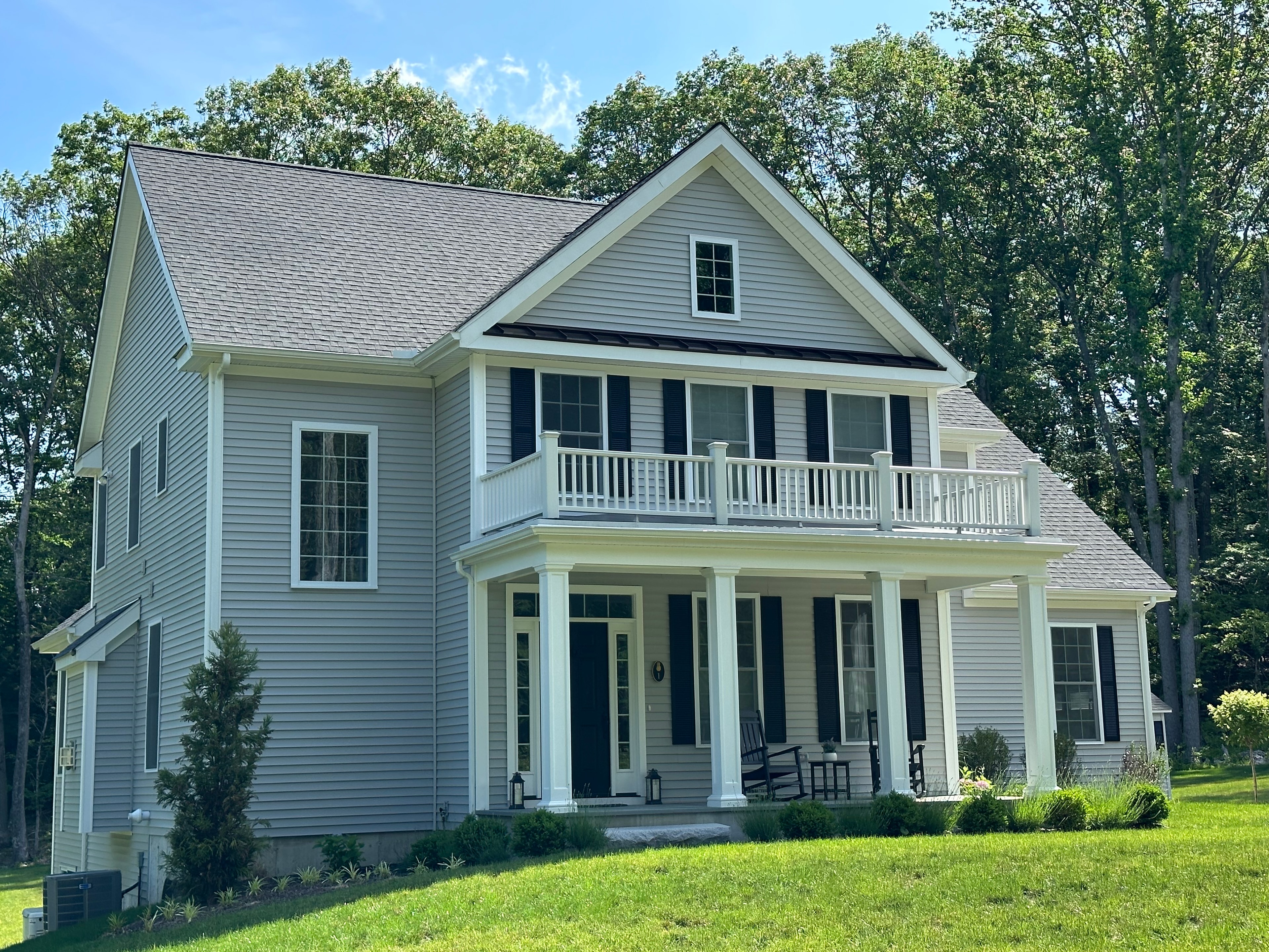 Light gray horizontal siding on a two-story home with white trim, a columned front porch and an upper balcony.